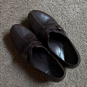 Pair of women's brown leather Dansko Tamara clogs with a buckle strap.